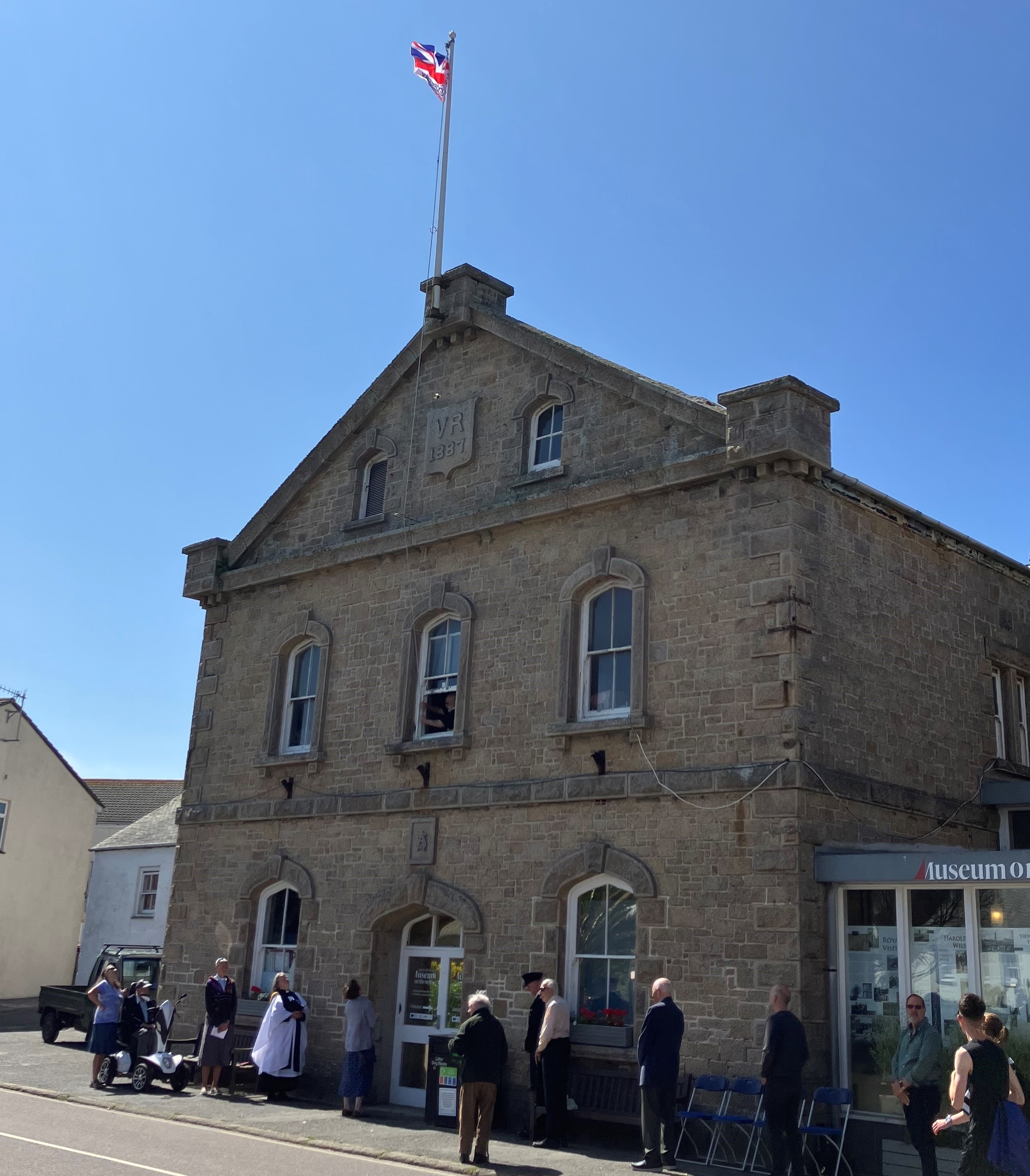 Image of the Armed Forces Day flag raised on the Town Hall with people gathered outside