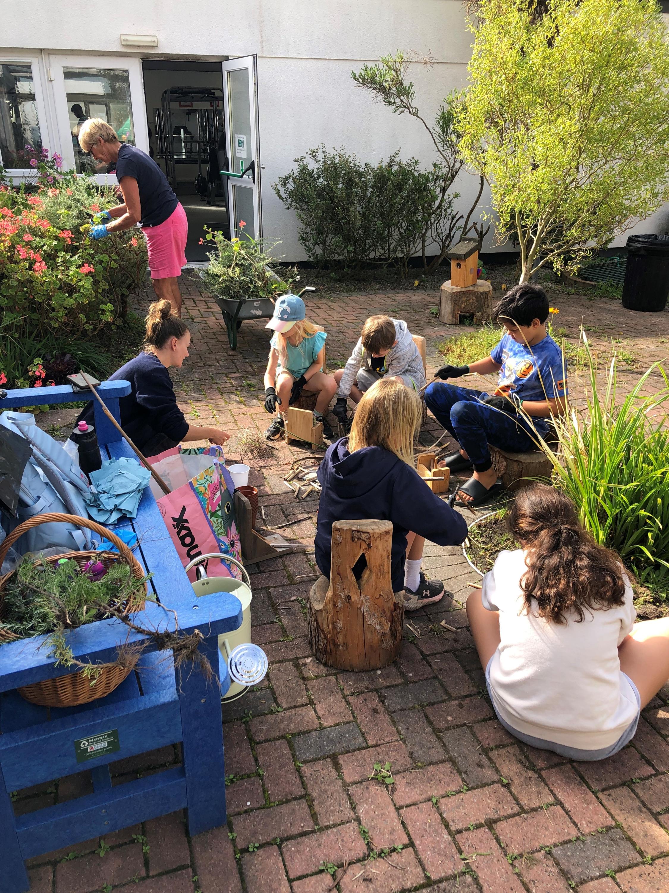 Image of an officer from the Isles of Scilly Wildlife Trust running a group activity for children and a volunteer working on the Community Garden