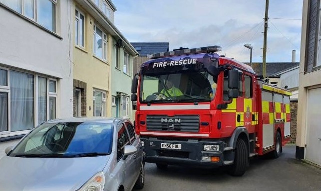 Image of the Isles of Scilly Fire and Rescue appliance turning a tight corner behind a parked car on St Mary's, Isles of Scilly.